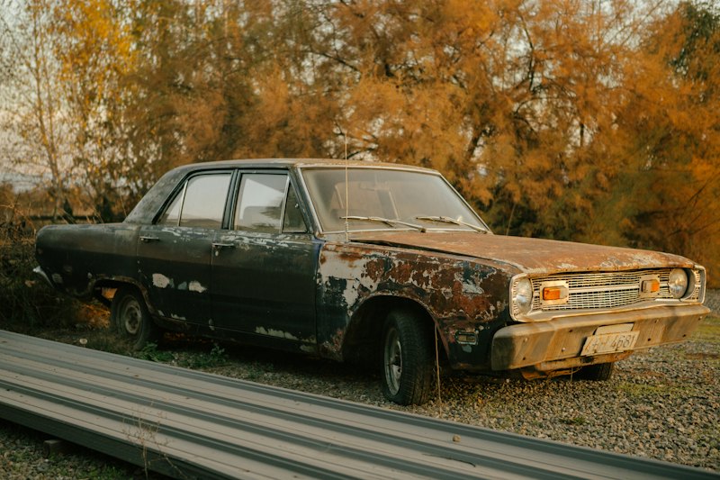 A rusted car parked on the side of a road
