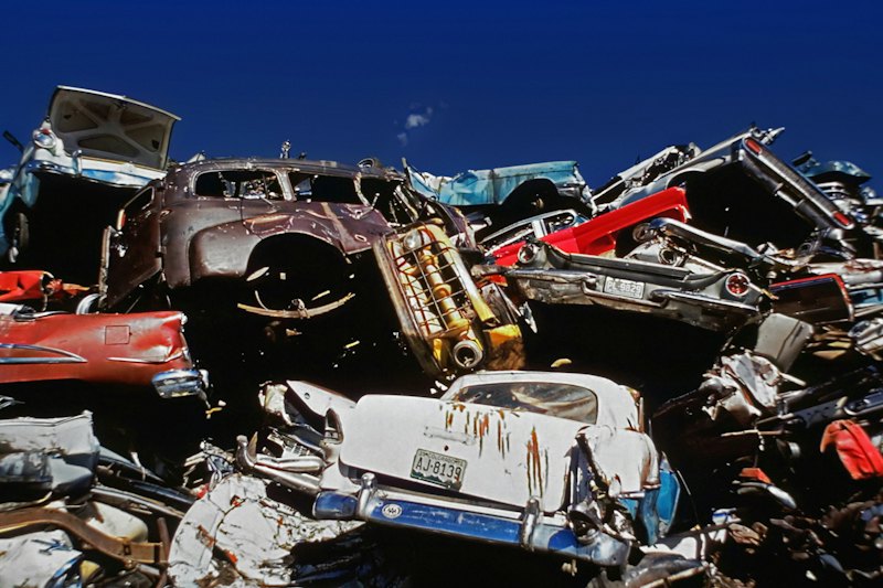 Old cars parked side by side in a junkyard