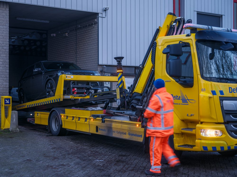 Driver in a safety vest beside a tow truck